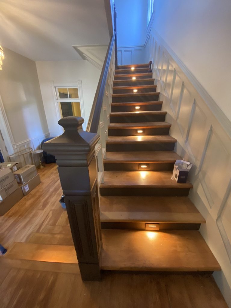 A wide wooden staircase with a small light set into every other riser.